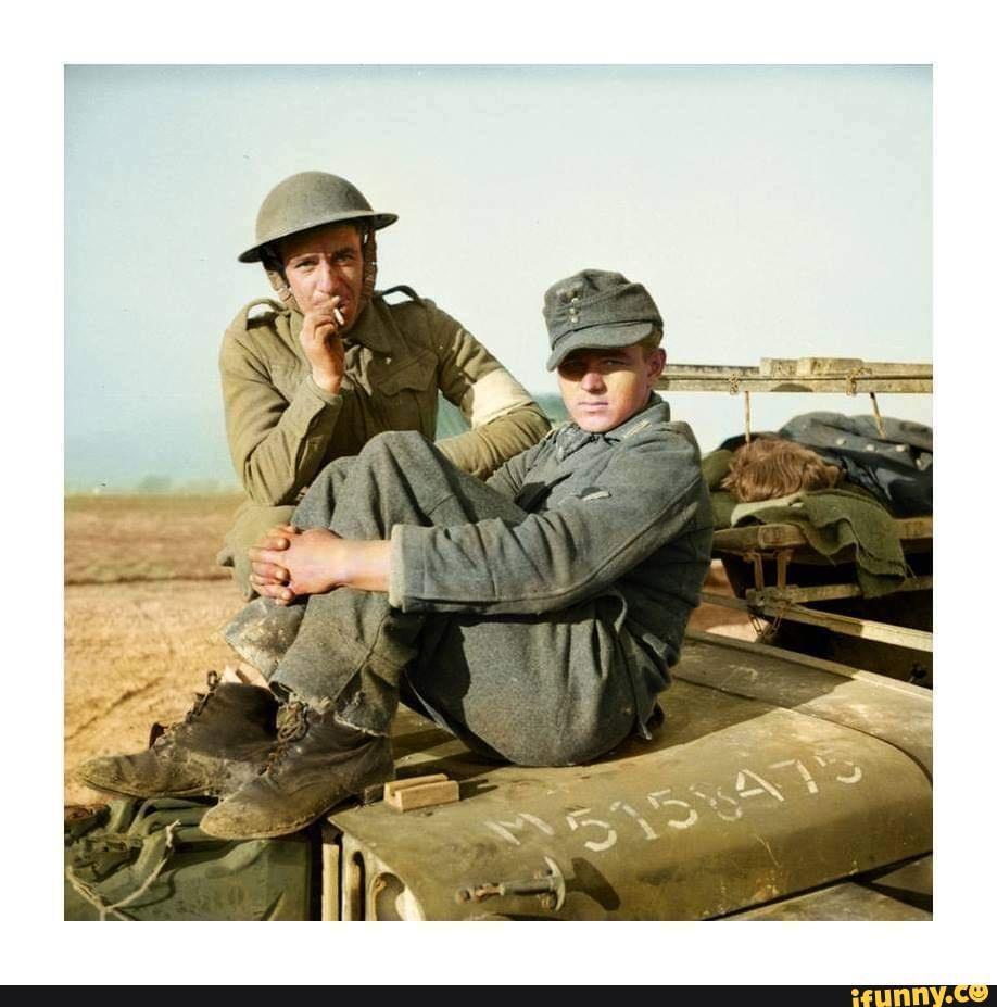 A British soldier with a young German prisoner sitting on the bonnet of ...